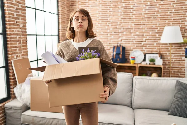 Young Beautiful Woman Holding Box Moving New Home Puffing Cheeks — стоковое фото