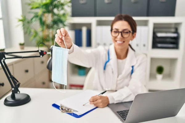 Young Hispanic Woman Wearing Doctor Uniform Holding Medical Mask Clinic — Stock Photo, Image