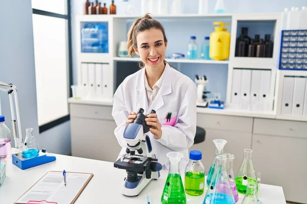 Νεαρή Γυναίκα Που Φοράει Επιστημονική Στολή Χρησιμοποιώντας Μικροσκόπιο Στο Εργαστήριο — Φωτογραφία Αρχείου