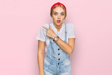 Gündelik giysiler giyen genç beyaz kız parmaklarını yana doğru göstererek şaşırdı, ağzı açık hayret içinde kaldı.. 