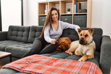 Kanepede oturmuş köpeklerle gülümseyen İspanyol bir kadın.