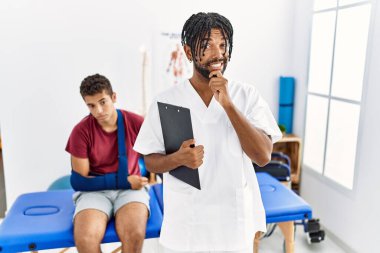 Kırık kollu bir adamla birlikte ağrı kesici kliniğinde çalışan genç İspanyol bir adam bir soru hakkında endişeli ve gergin bir şekilde düşünüyor. 