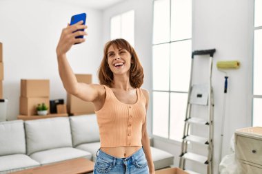 Beyaz kadın gülümsüyor. Kendine güveni tam. Evdeki akıllı telefonun yanında selfie çekiyor.