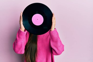Pembe arka planda retro vinil disk tutan kadın.
