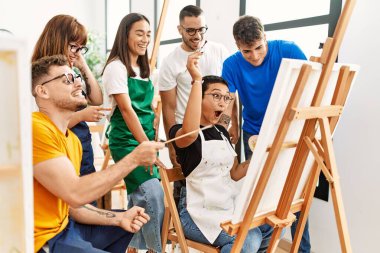 Mutlu gülümseyen ve ortak arayan bir grup insan sanat stüdyosunda..