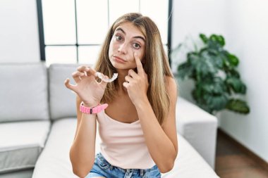 Görünmez hizada duran genç sarışın kadın gözüne işaret ediyor. Senin hareketlerini izliyor. Şüpheli bir ifade. 