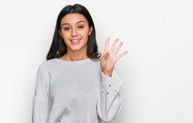 Latin kökenli genç bir kız günlük kıyafetler giyer ve parmaklarıyla dört numarayı gösterir.. 