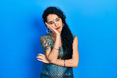 Bindi ve geleneksel kurta elbisesi giyen genç bir kadın kollarını kavuşturarak depresyondan sıkılmış ve yorgun göründüğünü düşünüyor.. 