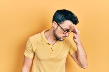 Gündelik kıyafetler ve gözlük takan genç İspanyol adam yorgun burnu ve gözleri ovuşturup yorgunluk ve baş ağrısı hissediyor. Stres ve hüsran kavramı. 