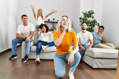 Bir grup genç arkadaş evde mikrofon kullanarak şarkı söylüyor..