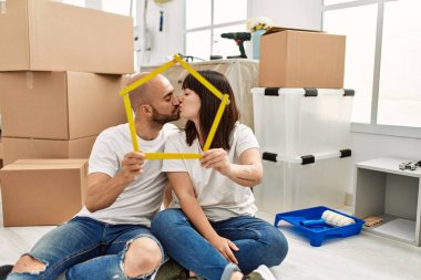 Genç İspanyol çift yeni evlerinde öpüşüyor ve ev projelerini tutuyorlar..