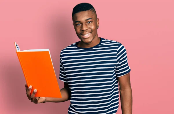 Młody Afrykanin Amerykański Mężczyzna Trzyma Książkę Patrząc Pozytywnie Szczęśliwy Stojąc — Zdjęcie stockowe