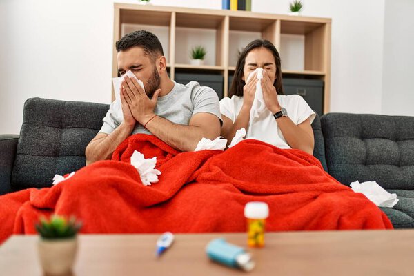 Young latin ill couple using napkin sititng on the sofa at home.