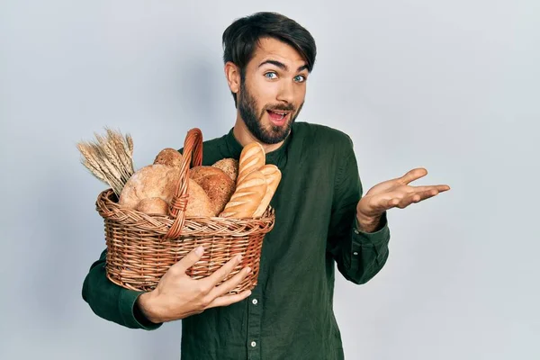 Молодий Іспаномовний Чоловік Тримає Плетений Кошик Хлібом Святкуючи Досягнення Щасливою — стокове фото
