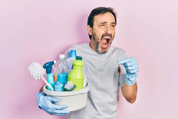 Middle Age Hispanic Man Holding Cleaning Products Holding Cockroach Angry — 图库照片