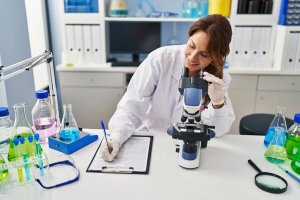 Giovane Donna Latina Uniforme Scienziato Con Scrittura Microscopica Sugli Appunti — Foto Stock