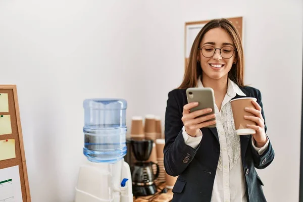 オフィスでスマートフォンやコーヒーを使用して若いヒスパニック系女性のビジネスワーカー — ストック写真