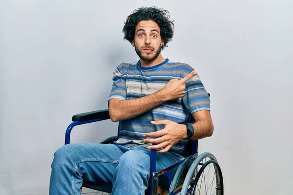 Handsome Hispanic Man Sitting Wheelchair Pointing Aside Worried Nervous Forefinger — Stockfoto
