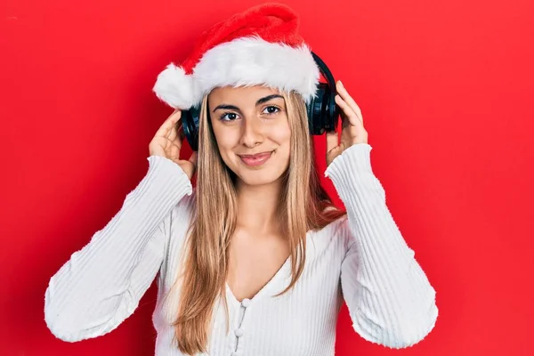 Schöne Hispanische Frau Mit Weihnachtsmütze Und Kopfhörer Entspannt Mit Ernstem — Stockfoto