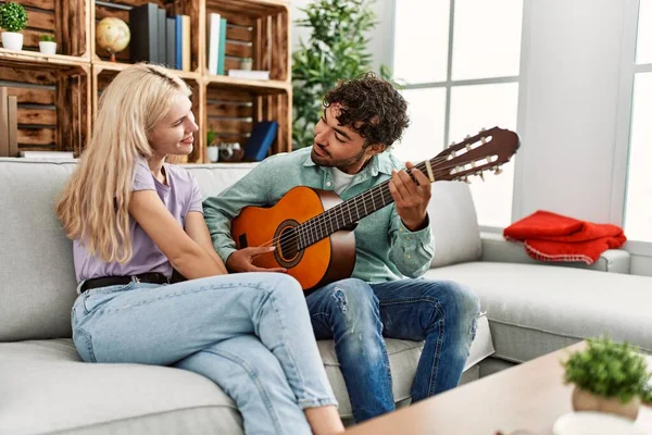 Mężczyzna Gra Hiszpańskiej Gitarze Swojej Dziewczyny Siedzi Kanapie Domu — Zdjęcie stockowe