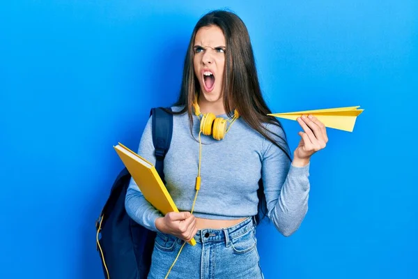 Junge Brünette Teenagerschülerin Mit Büchern Und Papierflugzeug Wütend Und Wütend — Stockfoto