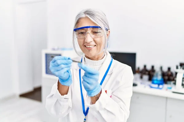 Middle Age Grey Haired Woman Wearing Scientist Uniform Holding Tweezer — Zdjęcie stockowe