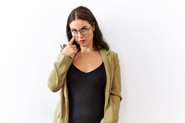 Genç esmer kadın izole edilmiş arka planda dikiliyor. Gözü işaret ediyor. Senin hareketlerini izliyor. 