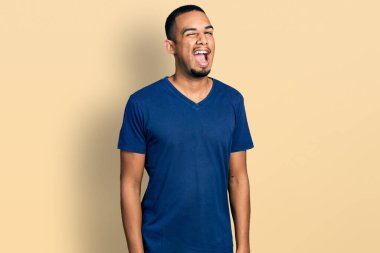 Gündelik tişört giyen genç Afro-Amerikan adam kameraya seksi bir ifadeyle bakıyor, neşeli ve mutlu bir yüzle.. 