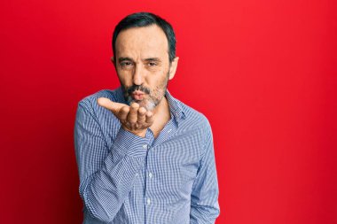 Orta yaşlı İspanyol bir adam, gündelik kıyafetler giyip kameraya bakıyor ve havada el sallayarak öpüşüyor. Güzel ve seksi. aşk ifadesi. 