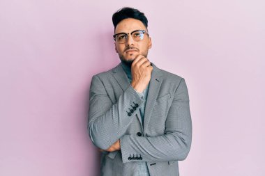 İş kıyafetleri giymiş genç bir Arap, şüpheye odaklanmıştı. Parmakları çenesinde ve yukarı bakıyordu. 