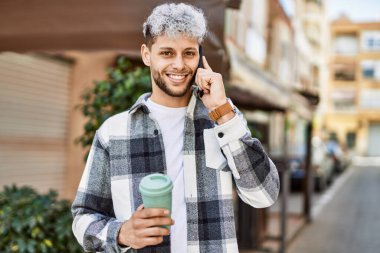 Genç İspanyol adam akıllı telefondan konuşuyor. Şehirde kahve içiyor..