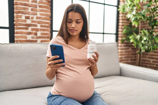 Giovane Donna Latina Incinta Utilizzando Smartphone Contenente Bottiglia Pillole Casa — Foto Stock