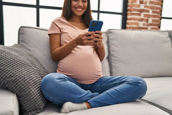 Νεαρή Λατίν Γυναίκα Έγκυος Χρησιμοποιώντας Smartphone Στο Σπίτι — Φωτογραφία Αρχείου