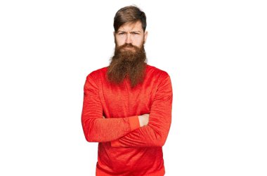 Uzun sakallı, sıradan kıyafetler giyen, kuşkucu ve gergin, yüzünde çapraz kollu tasvip etmeyen bir ifade olan kızıl saçlı adam. negatif kişi. 