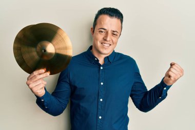 Altın zilli tabakları tutan yakışıklı genç adam gururla haykırıyor, zaferi kutluyor ve başarıyı kollarını kaldırarak heyecanlanıyor. 