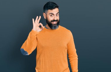 Sakallı, sıradan bir kazak giyen, gülümseyen İspanyol adam el ve parmaklarıyla 