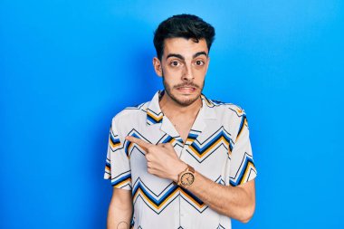 Gündelik kıyafetler giyen genç İspanyol adam endişeli ve gergin bir şekilde işaret ediyor. 