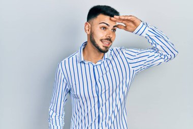 Sakallı, sıradan çizgili tişörtlü, mutlu ve tebessüm eden genç bir İspanyol. arama kavramı. 