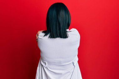Genç İspanyol kadın doktor üniforması giyiyor ve steteskop takıyor mutlu ve pozitif bir şekilde kendini kucaklıyor. Sevgi ve özgüven. 