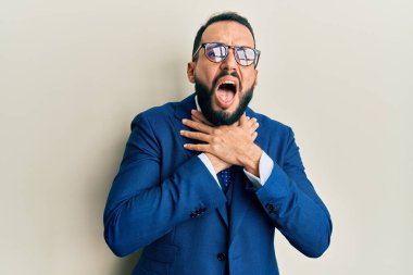 Sakallı, takım elbiseli ve kravatlı genç adam bağırıyor ve boğuluyor çünkü acı verici bir boğulma. Sağlık problemi. Boğulma ve intihar konsepti. 