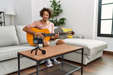 Evde klasik gitar çalan Latin asıllı genç bir adam kayıt yapıyor..