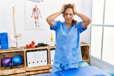 Orta yaşlı İspanyol fizyoterapist kadın ağrı kesici kliniğinde çalışıyor. Ağrı ve migren yüzünden çaresiz ve stresli. Eller başının üstünde.. 