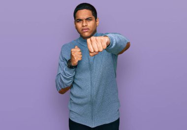 Yakışıklı İspanyol bir adam, sıradan bir kazak giyiyor dövüşmek için yumruk atıyor agresif ve öfkeli bir saldırı, tehdit ve şiddet. 