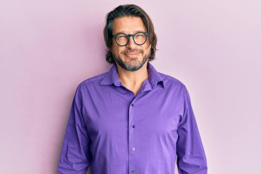 Yüzünde mutlu ve havalı bir gülümseme olan sıradan kıyafetler ve gözlük takan orta yaşlı yakışıklı bir adam. şanslı kişi. 