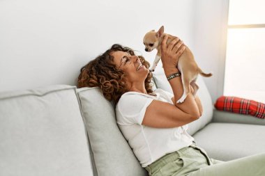 Orta yaşlı İspanyol kadın gülümsüyor, elinde Chihuahua ile.