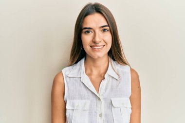 Kendine güvenen güzel genç bir kadın kameraya bakıp gülümsüyor.