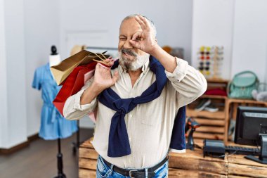 Yakışıklı son sınıf öğrencisi butik dükkanında alışveriş torbaları tutuyor gülümsüyor mutlu mesut gülümsüyor. 