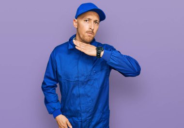 Sakallı, işçi tulumu giyen, boğazını bıçak niyetine kesen, saldırganlığı şiddetle tehdit eden kel bir adam. 