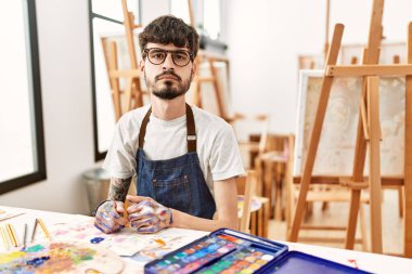 Sanat stüdyosundaki sakallı İspanyol adam yüzünde ciddi bir ifadeyle rahatladı. Basit ve doğal bir şekilde kameraya bakıyorsun.. 