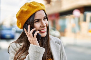 Genç İspanyol kız gülümsüyor. Şehirdeki akıllı telefondan konuşuyor..